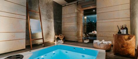 Un área de spa moderna con un jacuzzi grande, suelo de madera y vistas al baño.