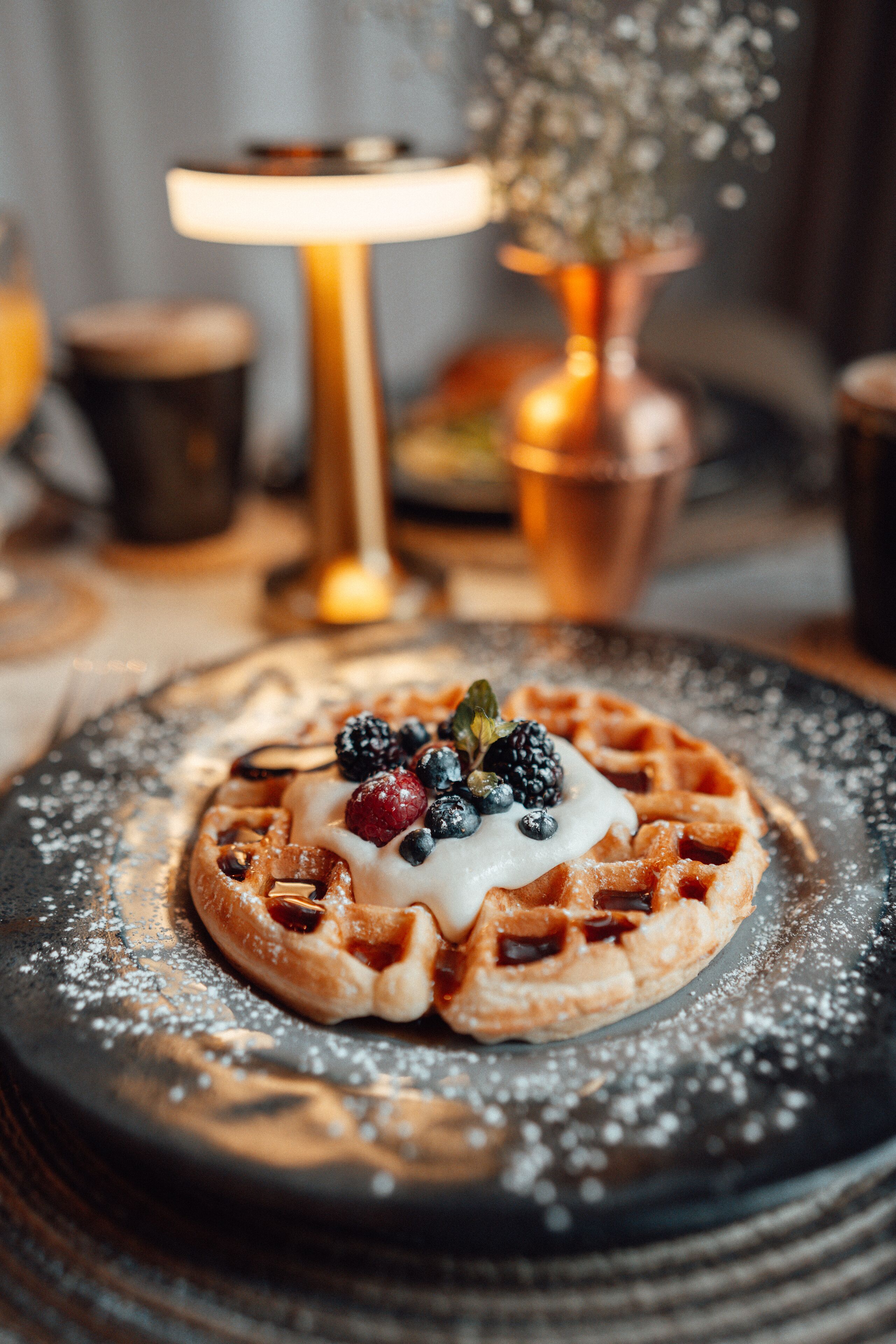 A close-up of a dessert with berries and powdered sugar on a plate.