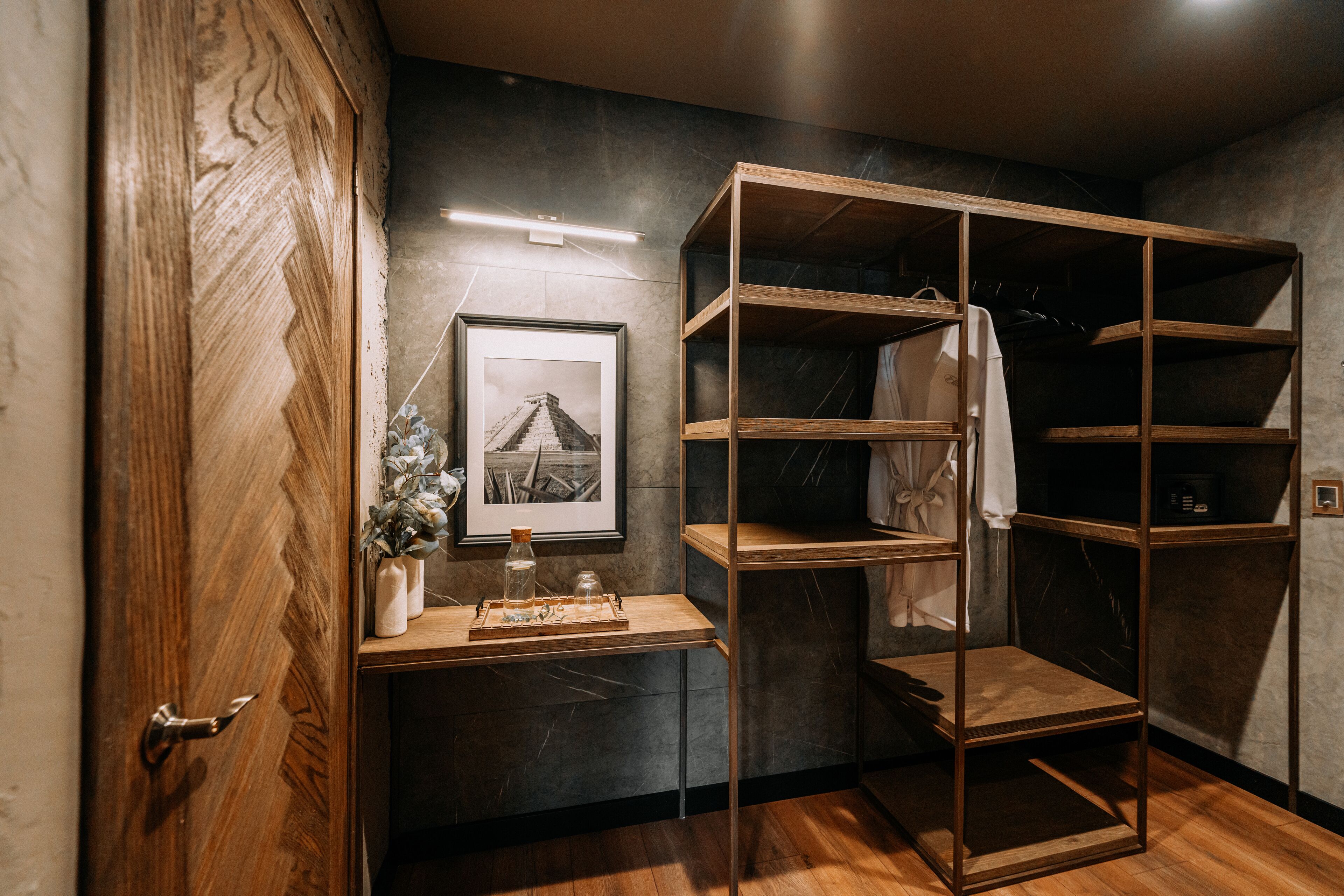 A modern bathroom with a wooden vanity, a framed picture, and a shelf unit.