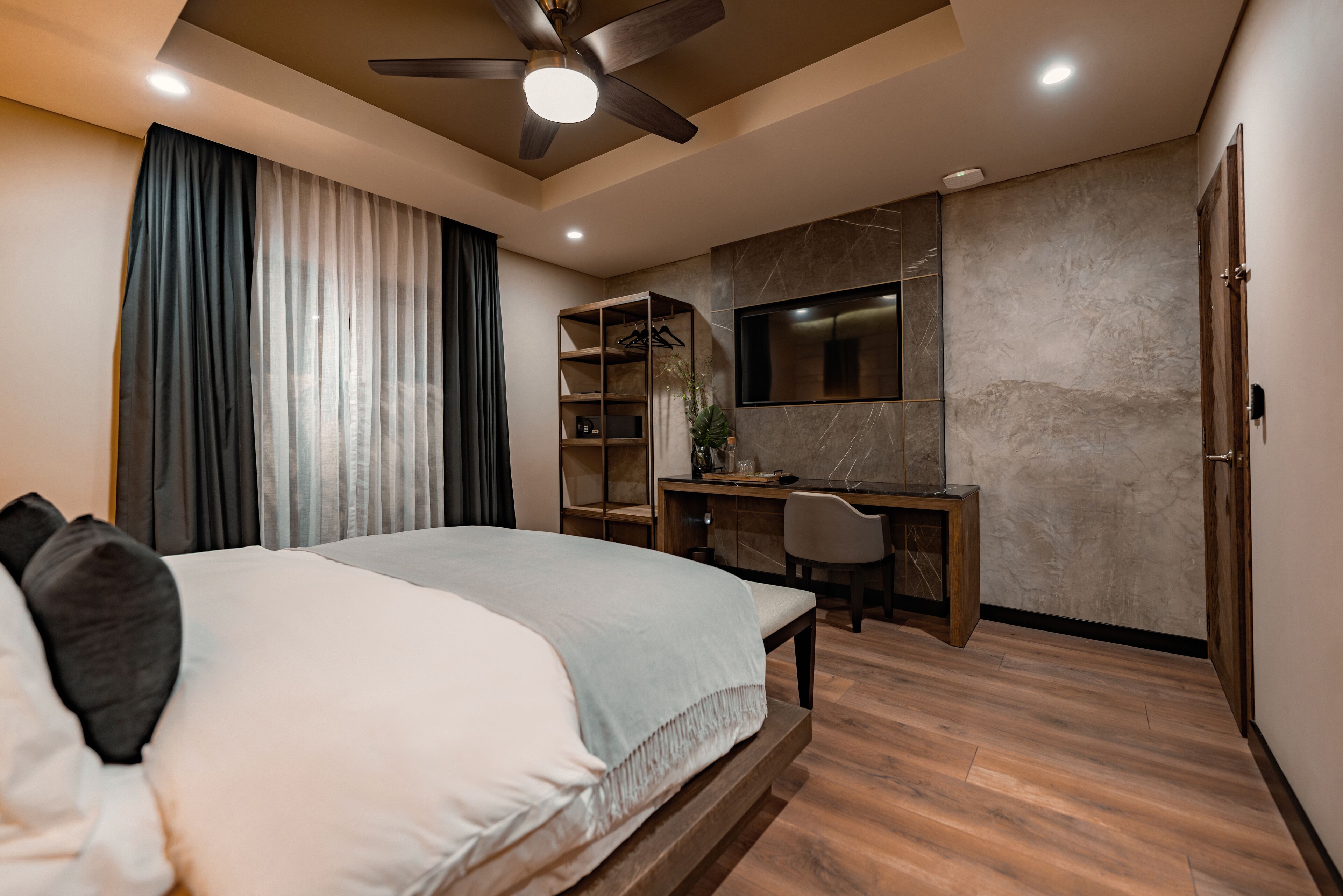 A bedroom with a bed, desk, chair, TV, and wardrobe.