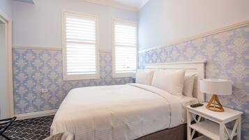 A bedroom with a bed, white nightstand, and a lamp.