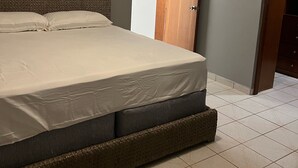 Ein Schlafzimmer mit Bett, Klimaanlage, Kleiderschrank und Fliesenboden.