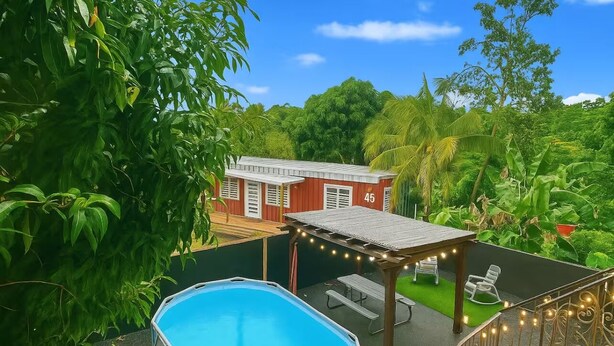 Ein Pool mit einer Pergola, Sitzgelegenheiten im Freien und ein rotes Gebäude mit der Nummer 45.