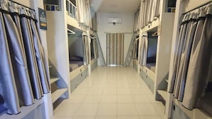 A corridor with bunk beds, curtains, and a tiled floor. - Bunk Bed Room Nusa Penida - Hostel (Penida Island)