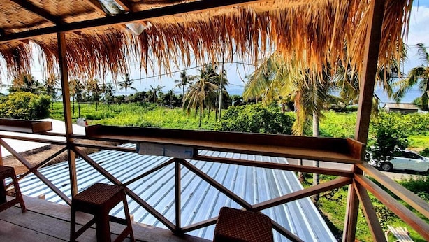 A covered outdoor area with a view of a lush green landscape and palm trees. - Bunk Bed Room Nusa Penida - Hostel (Penida Island)