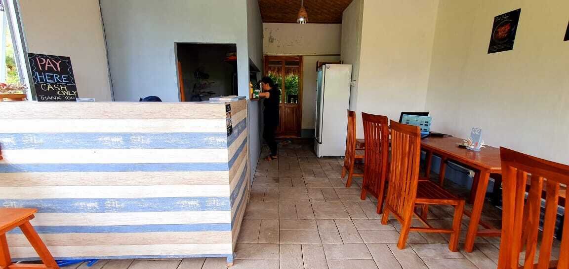 Zona de recepción con mostrador de madera, un cartel que indica pago en efectivo y un refrigerador al fondo.