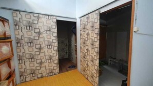 A room with a patterned wall, a wooden floor, and a doorway leading to another room. - Bunk Bed Room Nusa Penida - Hostel (Penida Island)