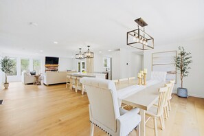 Een ruime woonkamer met een eettafel, stoelen, een bank en een televisie.