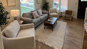 Un salon comprenant un canapé, des fauteuils, une table basse et un tapis.