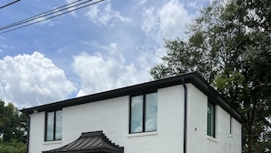 Un bâtiment moderne à deux étages, avec une façade blanche, un porche et un parking.
