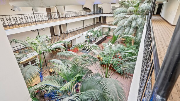 A multi-level atrium with a central garden area featuring palm trees and potted plants. - Coratel Suites Deluxe 1 King Suite with Sofa Oversized Non Smoking (Wichita)