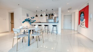 A modern kitchen with white cabinets, a stainless steel refrigerator, and a central island with bar stools. - Maison Privee - Aesthetic Apt w/ Stunning Vw in Luxurious Building (Dubai)