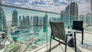 A balcony with a glass railing overlooking a marina and a cityscape. - Maison Privee - Aesthetic Apt w/ Stunning Vw in Luxurious Building (Dubai)