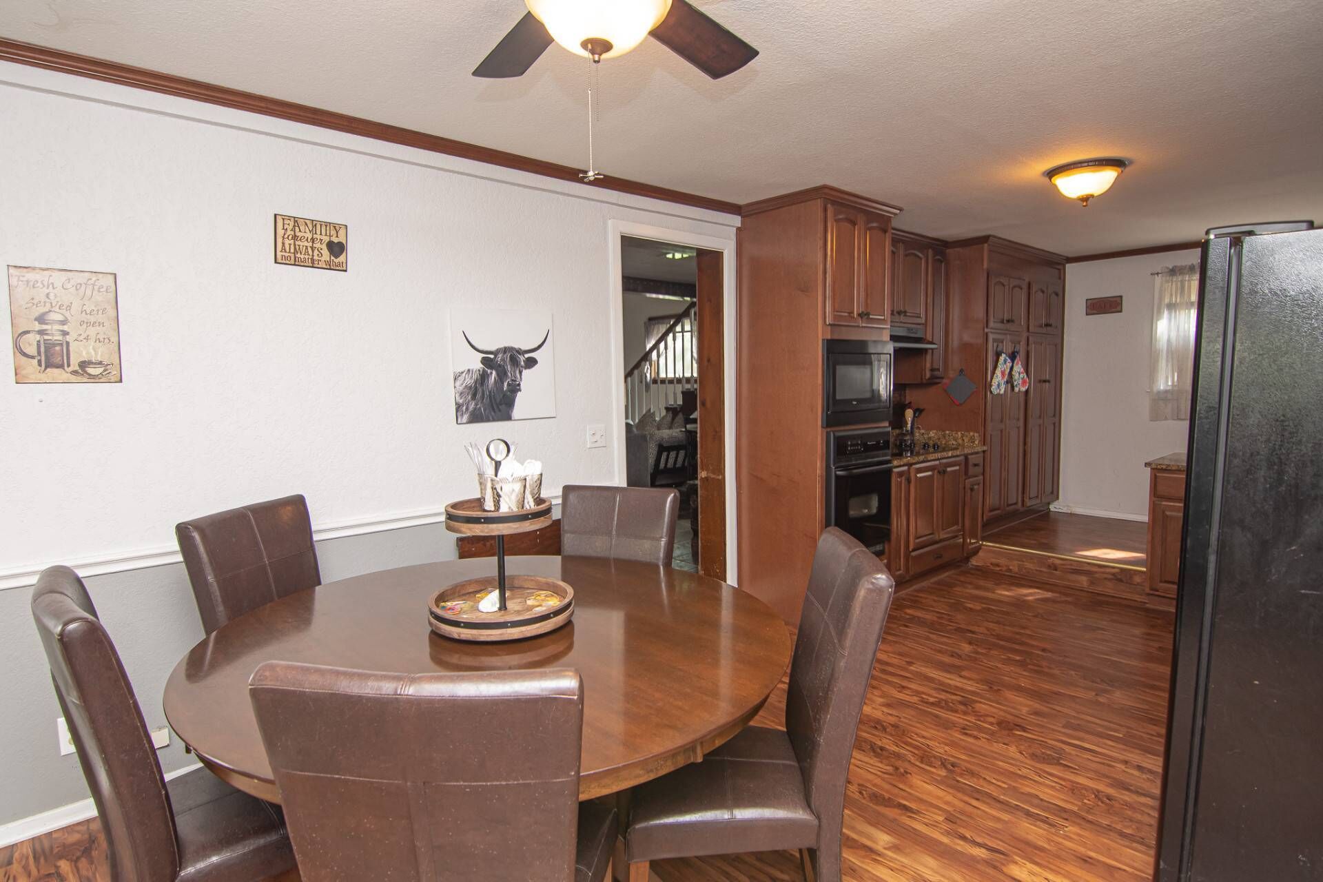 A dining area with a round table, six chairs, and a ceiling fan.