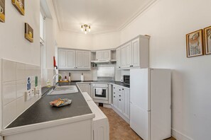 A modern kitchen with white cabinetry, a black countertop, and a built-in oven.