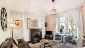 Una sala de estar con chimenea, una mesa redonda de centro, un sofá, un televisor y un comedor con sillas y una mesa.