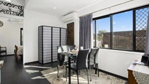 A dining area with a table and chairs, a decorative screen, and a view through a large window. - Modern 2 bedroom Unit in the beautiful Scenic Rim (Rathdowney)