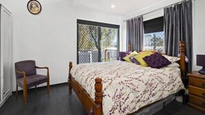 A bedroom with a bed, a chair, a dresser, and a window with curtains. - Modern 2 bedroom Unit in the beautiful Scenic Rim (Rathdowney)