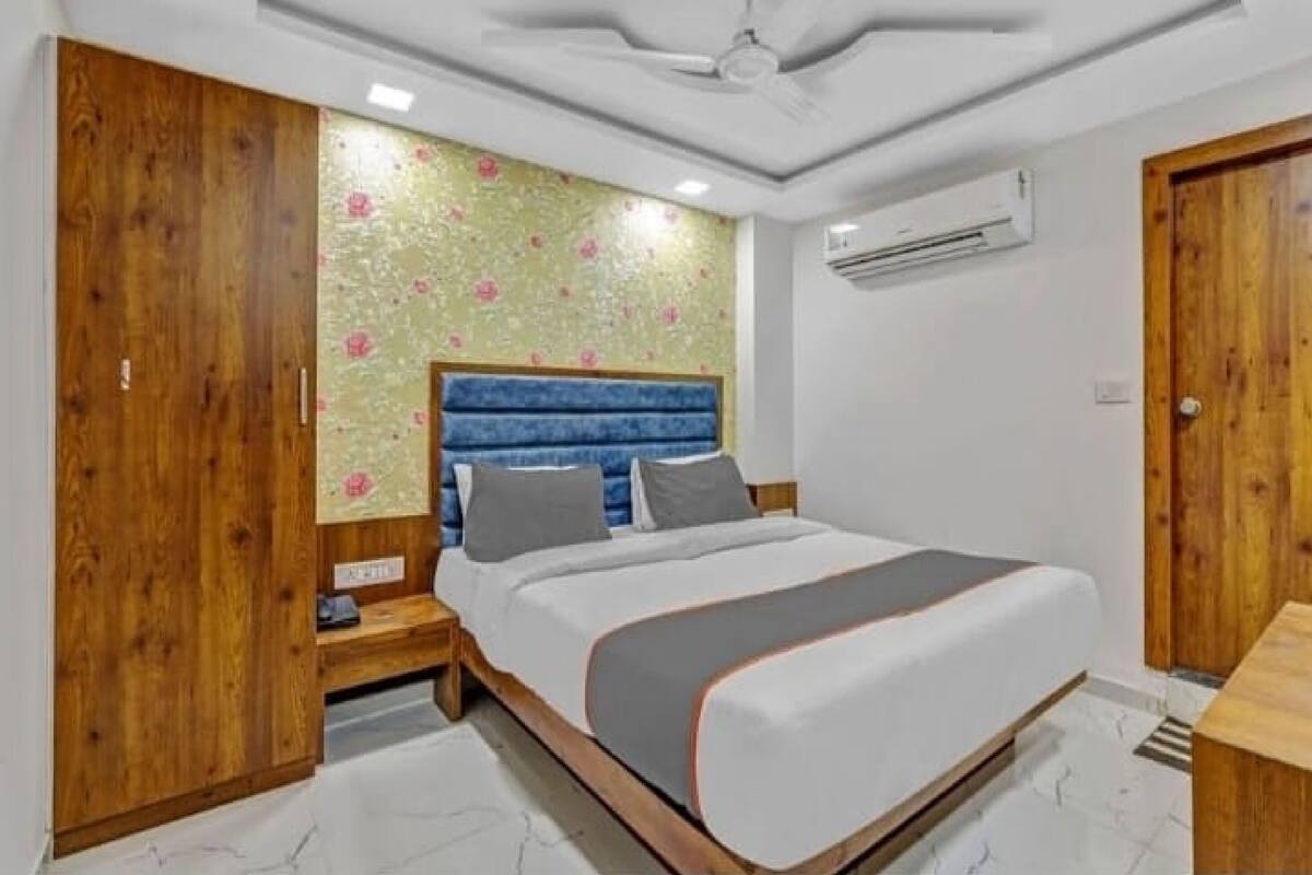 A bedroom with a bed, wooden wardrobe, and a ceiling fan.