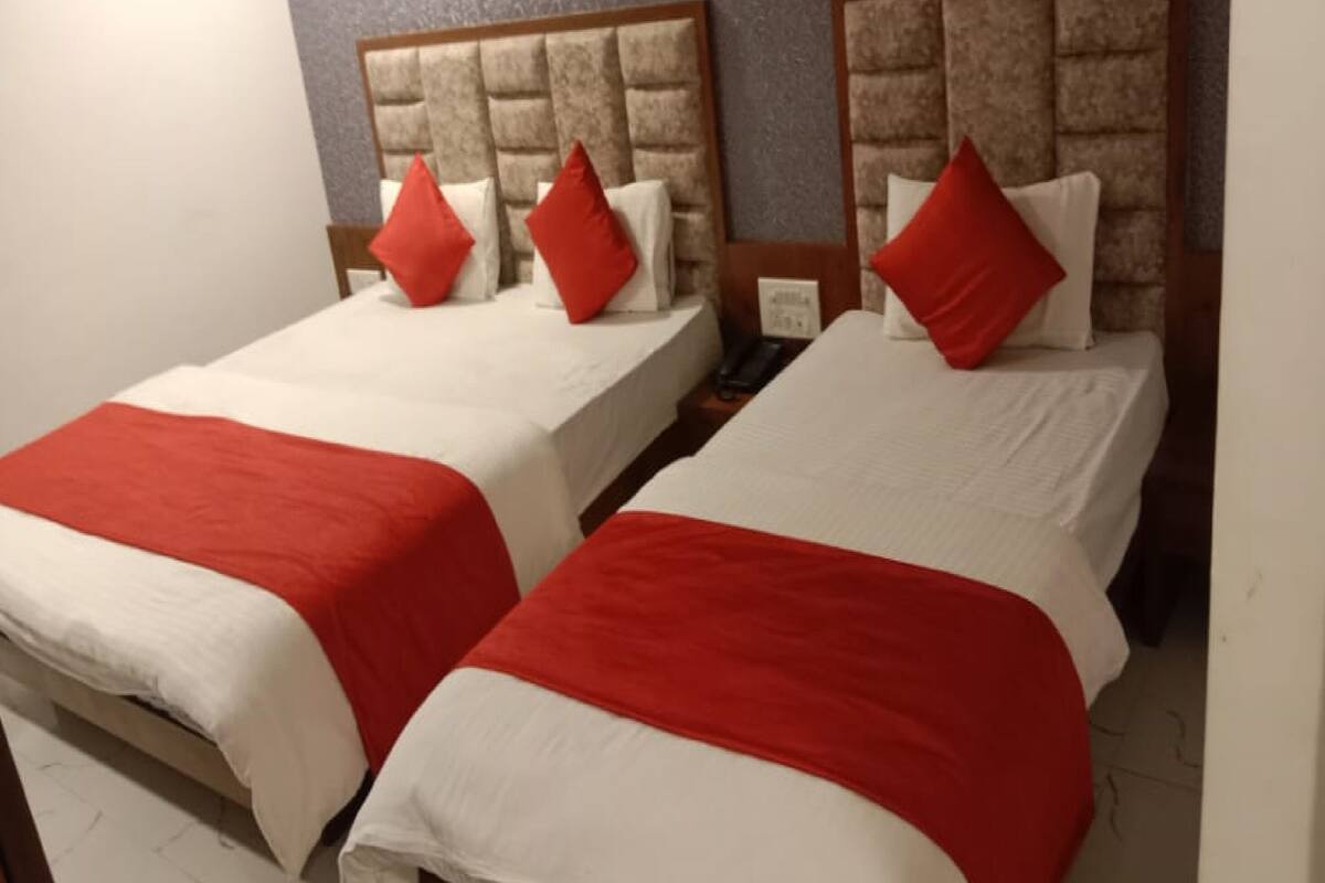 Two single beds with red and white bedding, wooden headboards, and a small bedside table with a phone.