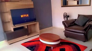 Ein Wohnzimmer mit einer Holzeinrichtungsanlage, einem braunen Ledersofa, einem runden Holztisch und einem roten und schwarzen Teppich.