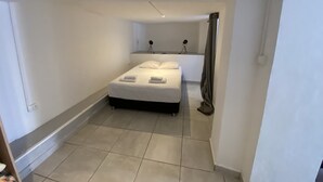 A small, clean room with a bed, a desk, and a chair. - Appart Quattro (Saint Paul)