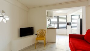 A living room with a flat-screen TV, a yellow chair, and a red sofa. - Appart Quattro (Saint Paul)
