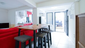 A compact living space with a dining area, a red sofa, and a television. - Appart Quattro (Saint Paul)