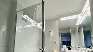 Ein modernes Badezimmer mit Duschkabine aus Glas, Toilette, Waschbecken und Spiegel.