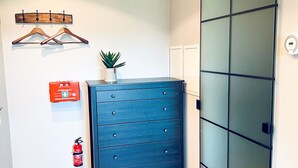 A room with a wooden floor, a blue dresser, a wall-mounted plant, a fire extinguisher, and a sliding door with frosted glass panels. - Industrial Loft Urban. Living. Trier (Trier)