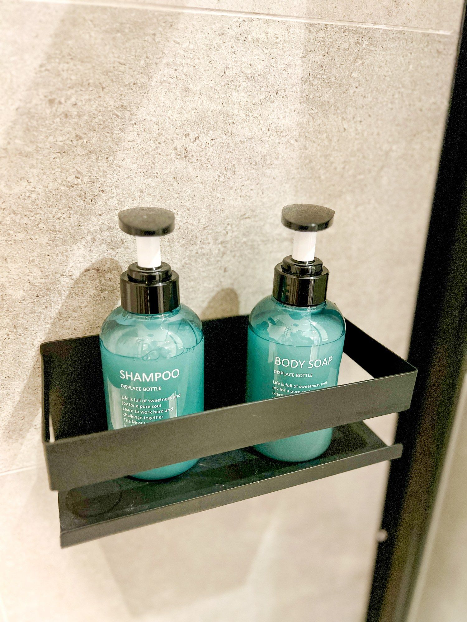 Une étagère de salle de bain avec deux bouteilles de savon pour le corps et de shampoing.