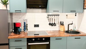 A modern kitchen with light blue cabinets, a stainless steel refrigerator, a coffee maker, and a built-in oven. - Industrial Loft Urban. Living. Trier (Trier)
