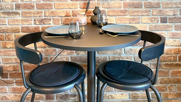 A round table with two chairs, a hanging lamp, and a framed picture on a brick wall. - Industrial Loft Urban. Living. Trier (Trier)