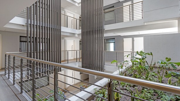 A multi-level interior with a central atrium, metal railings, and indoor plants. - Cosmopolitan 401 (Cape Town)