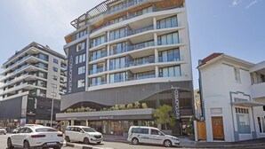 A modern multi-story hotel with balconies, a restaurant named "Carnifleurs," and a visible parking area. - Cosmopolitan 401 (Cape Town)