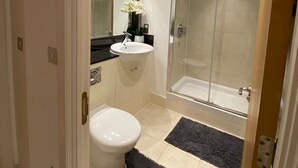 A modern bathroom with a toilet, sink, and glass shower enclosure.