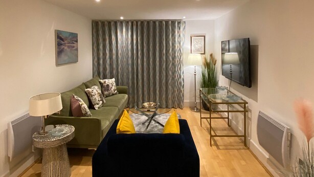 A modern living room with a sofa, a coffee table, a TV, and a lamp.