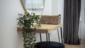 A room with a wooden table, a black cushioned chair, a wicker basket, and a hanging plant. - Blueberries Apartments by Sasco (Blackpool)