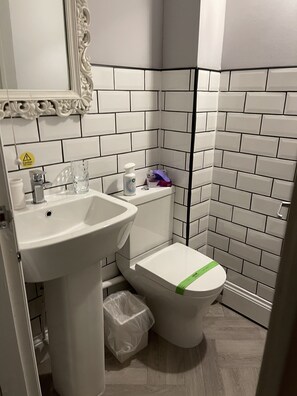 A bathroom with white tiles, a sink, a toilet, and a mirror.