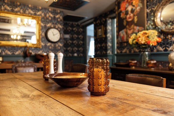 A wooden table with a decorative glass vase and salt and pepper shakers.