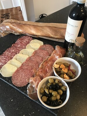 A charcuterie board with various meats, cheeses, and olives on a black countertop.
