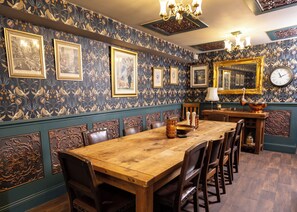 A dining area with a wooden table, chairs, and a wall with framed pictures. - The Old Clock Tower Central Skipton Luxury Apartment 60+ 5* Reviews on platforms (Skipton)