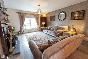 A living room with a sofa, a coffee table, a fireplace, and a window with curtains. - The Old Clock Tower Central Skipton Luxury Apartment 60+ 5* Reviews on platforms (Skipton)