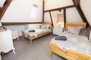 A bedroom with two beds, a nightstand, a dresser, and a window.