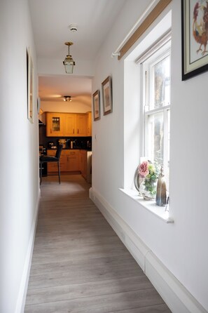 A hallway leading to a kitchen with wooden cabinets and a dining area. - The Old Clock Tower Central Skipton Luxury Apartment 60+ 5* Reviews on platforms (Skipton)