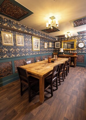 A dining room with a long wooden table, multiple chairs, framed pictures on the wall, and a chandelier. - The Old Clock Tower Central Skipton Luxury Apartment 60+ 5* Reviews on platforms (Skipton)