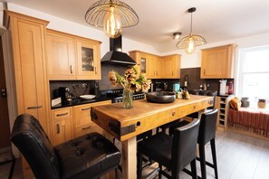 A modern kitchen with wooden cabinets, a central island, black bar stools, and pendant lighting.