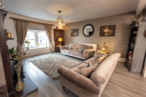 A living room with a sofa, a rug, a lamp, and a window with curtains. - The Old Clock Tower Central Skipton Luxury Apartment 60+ 5* Reviews on platforms (Skipton)