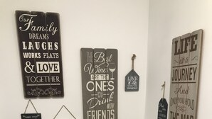 Un baño con inodoro, un mueble pequeño y un estante en la pared con una vela y un roll de pañuelos.