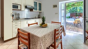 Une cuisine avec une table à manger, des chaises et une vue sur un patio extérieur.